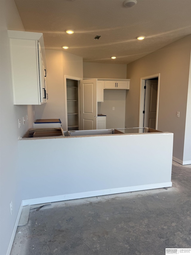 kitchen with white cabinets, baseboards, unfinished concrete floors, and recessed lighting