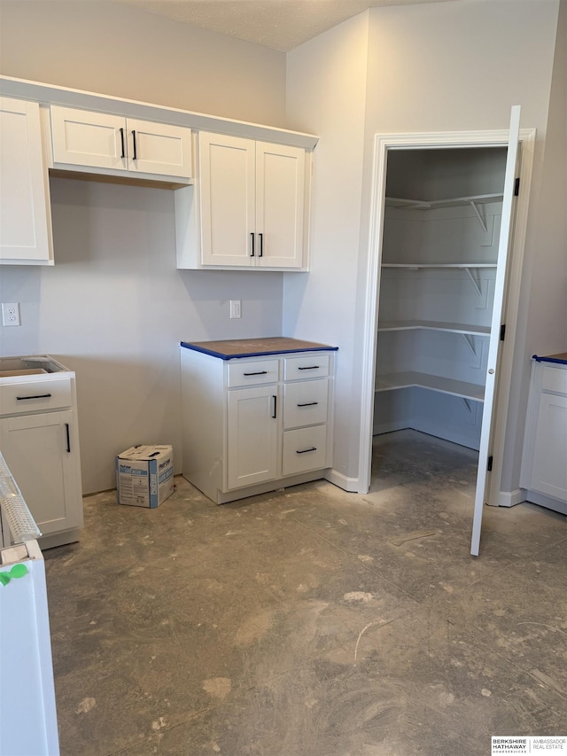 kitchen with unfinished concrete floors and white cabinets