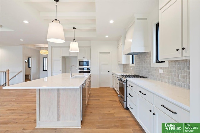 kitchen featuring an island with sink, white cabinets, stainless steel appliances, and pendant lighting