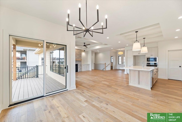 kitchen featuring a raised ceiling, built in microwave, a spacious island, decorative light fixtures, and white cabinetry