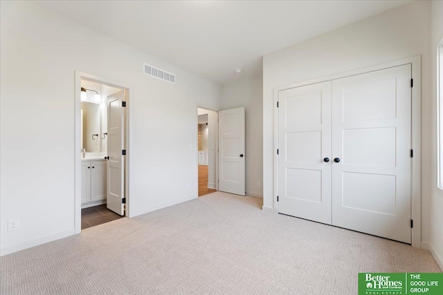 unfurnished bedroom featuring carpet flooring, ensuite bath, and a closet