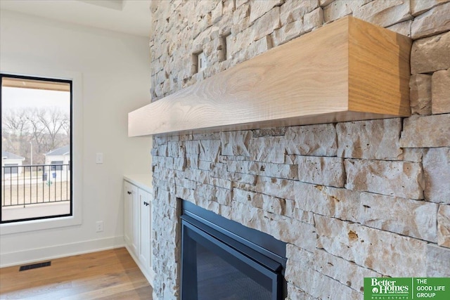 interior details with baseboards, a fireplace, visible vents, and wood finished floors