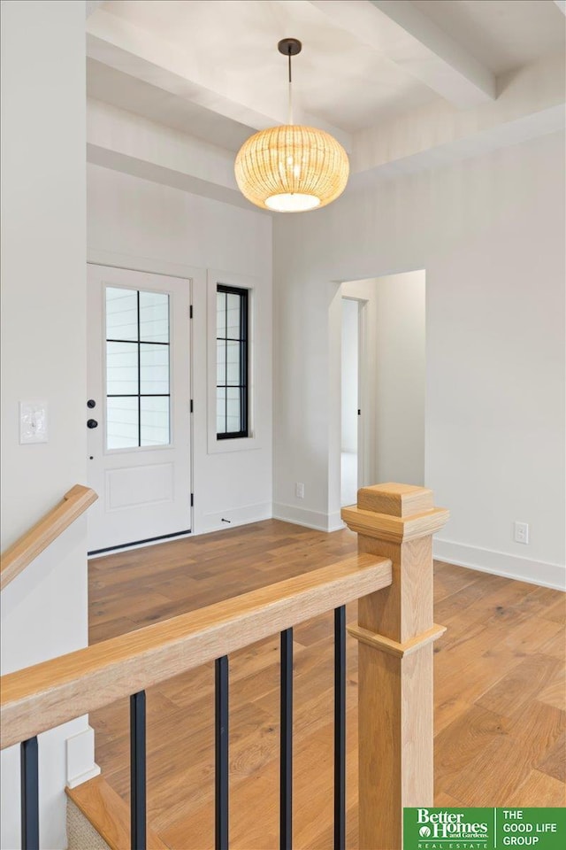 entryway featuring beam ceiling, baseboards, and wood finished floors