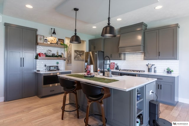 kitchen featuring decorative backsplash, custom range hood, stainless steel appliances, and light hardwood / wood-style flooring