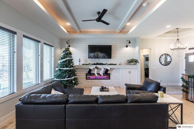 living room with plenty of natural light, light hardwood / wood-style floors, wooden walls, and a tray ceiling