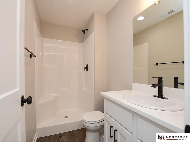 bathroom featuring hardwood / wood-style flooring, vanity, toilet, and walk in shower