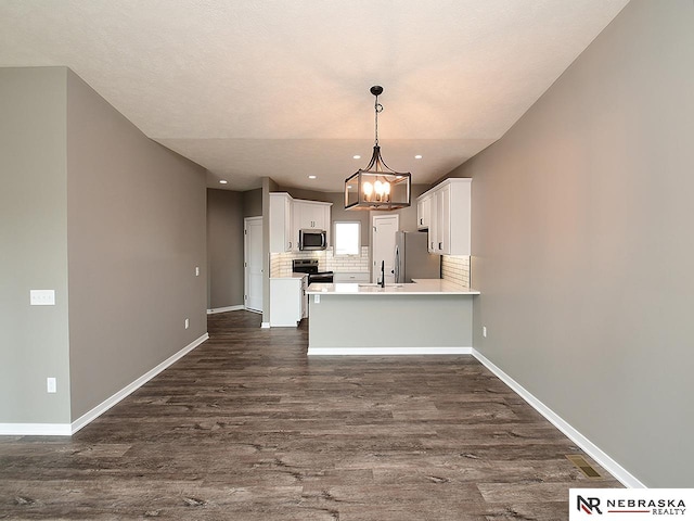 kitchen featuring pendant lighting, a notable chandelier, white cabinetry, kitchen peninsula, and stainless steel appliances