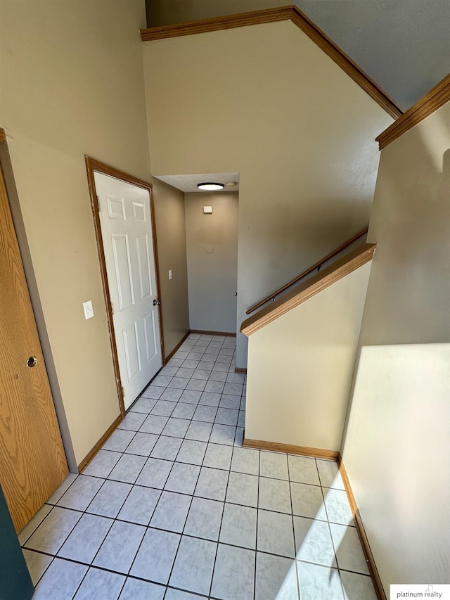 tiled foyer with crown molding and high vaulted ceiling