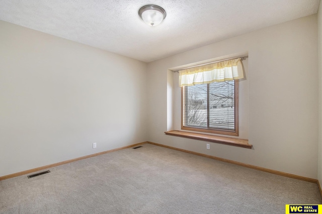 carpeted empty room featuring a textured ceiling