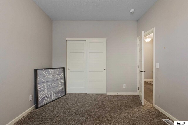 unfurnished bedroom featuring dark carpet and a closet