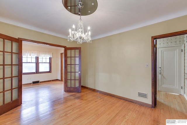 unfurnished room featuring french doors, light hardwood / wood-style flooring, and a notable chandelier