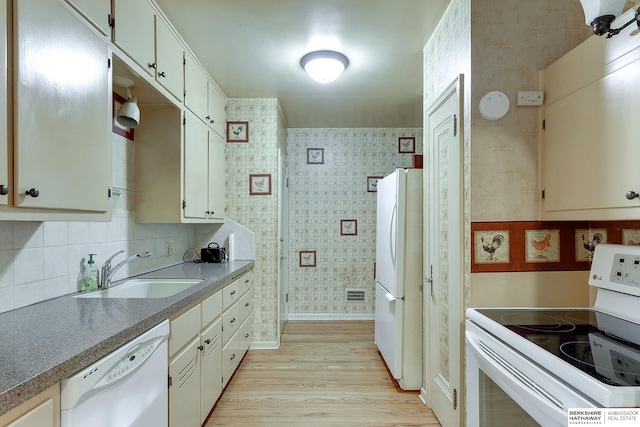 kitchen with decorative backsplash, white appliances, sink, and light hardwood / wood-style flooring