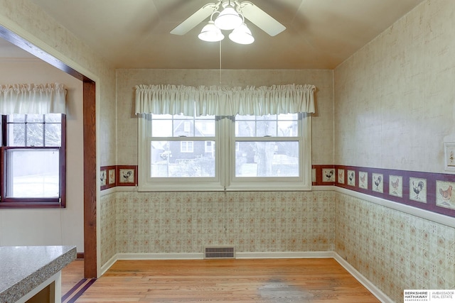 spare room featuring a wealth of natural light, ceiling fan, and light hardwood / wood-style flooring