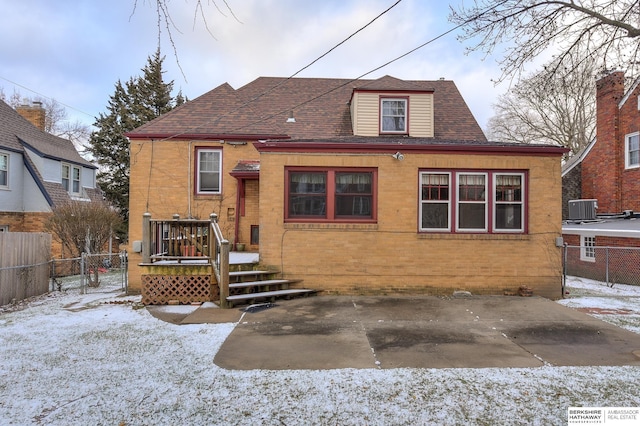 snow covered house featuring central AC unit