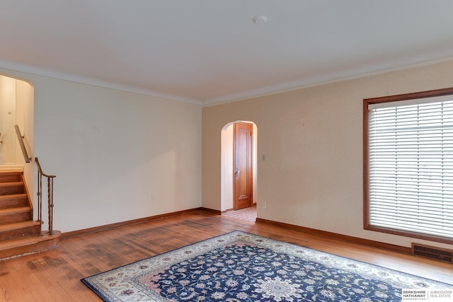 empty room with crown molding and light hardwood / wood-style flooring