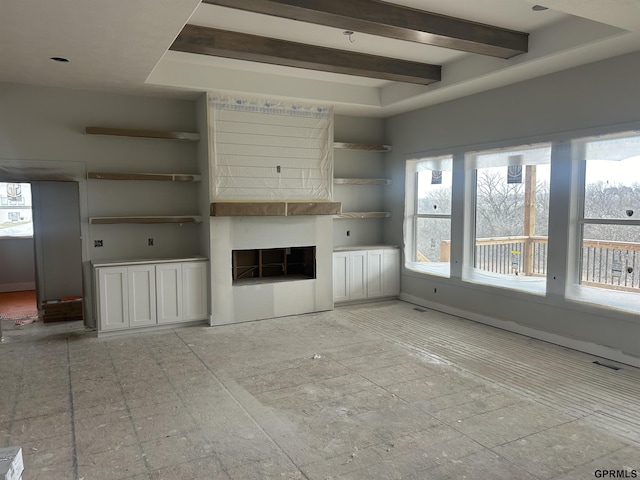 unfurnished living room with a fireplace and beam ceiling