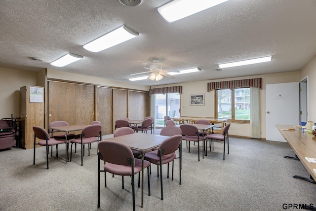 carpeted dining space with ceiling fan and a textured ceiling