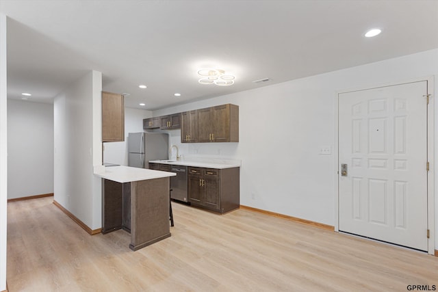 kitchen featuring stainless steel refrigerator, dark brown cabinetry, light hardwood / wood-style floors, and sink