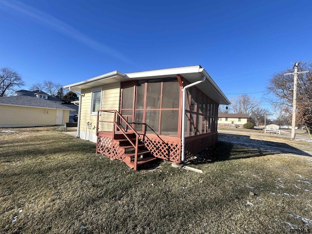 rear view of property with a yard and a sunroom