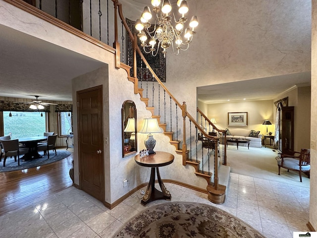 stairs with a towering ceiling, ceiling fan with notable chandelier, and a water view