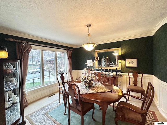 dining area with light carpet, a textured ceiling, and ornamental molding