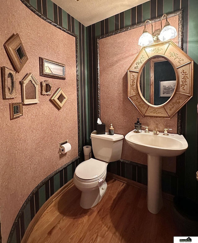 bathroom with toilet, wood-type flooring, and a textured ceiling