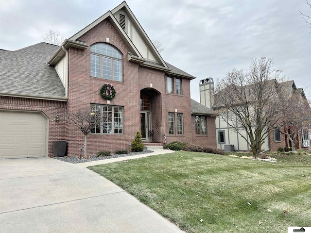 view of property featuring a front lawn, central AC unit, and a garage