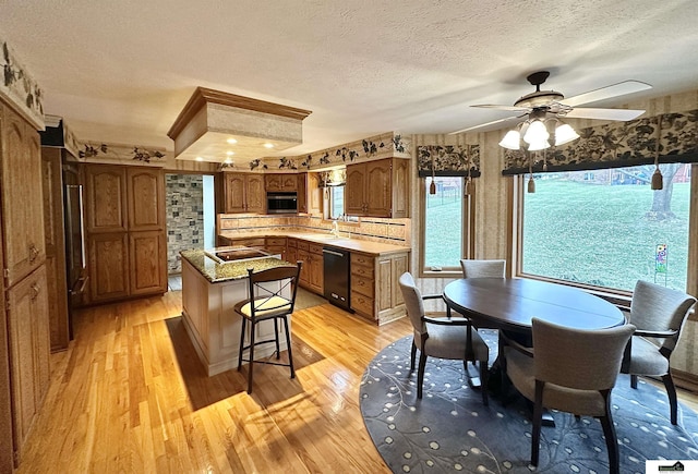 kitchen with backsplash, ceiling fan, dishwasher, and light wood-type flooring