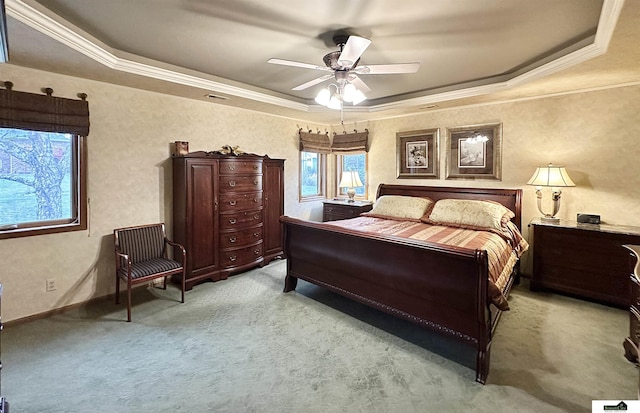 carpeted bedroom with a raised ceiling, ceiling fan, and ornamental molding