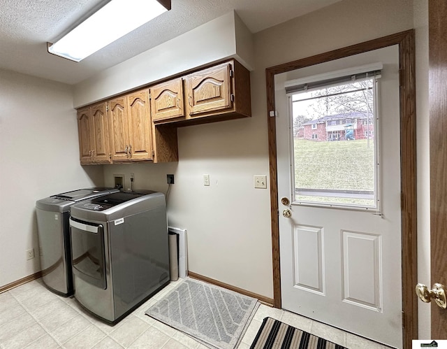 clothes washing area with a wealth of natural light, washer and clothes dryer, and cabinets