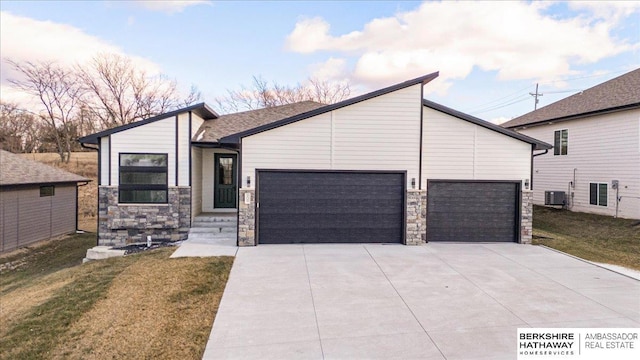 view of front of house featuring central AC, a garage, and a front lawn