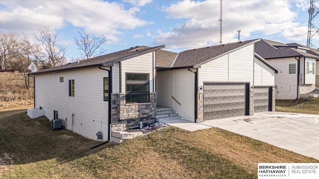 view of front of house featuring central air condition unit, a front yard, and a garage