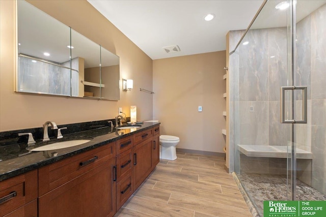 bathroom with walk in shower, vanity, and toilet