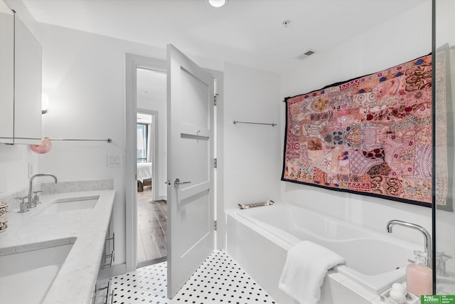 bathroom featuring tiled bath and vanity