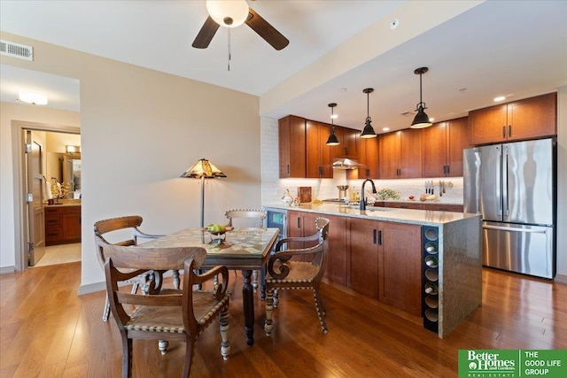 kitchen with pendant lighting, backsplash, ceiling fan, stainless steel fridge, and kitchen peninsula