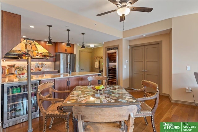 dining space with light wood-type flooring, beverage cooler, and ceiling fan