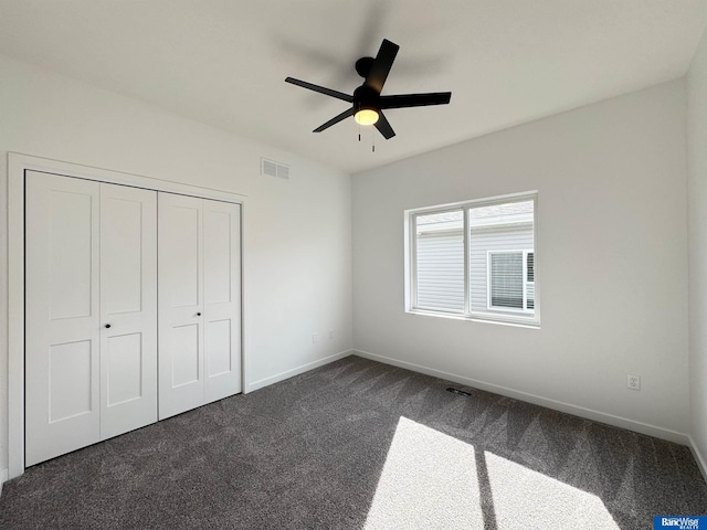 unfurnished bedroom featuring ceiling fan, a closet, and dark carpet