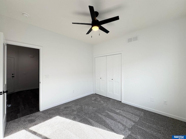 unfurnished bedroom with dark colored carpet, a closet, and ceiling fan