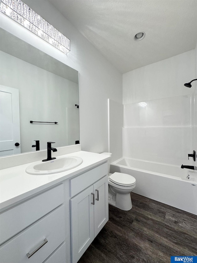 full bathroom with vanity, a textured ceiling, wood-type flooring, shower / bathing tub combination, and toilet