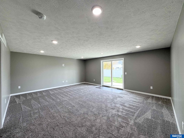 unfurnished room with dark carpet and a textured ceiling