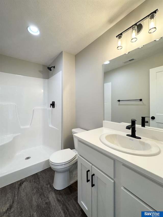 bathroom with a textured ceiling, vanity, a shower, wood-type flooring, and toilet