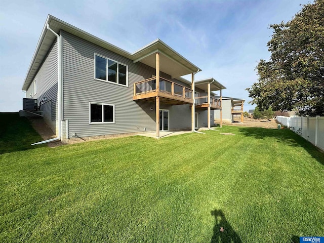 rear view of house featuring a deck, cooling unit, a patio area, and a lawn