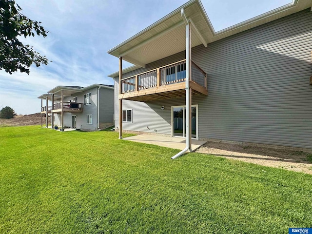 back of property featuring a yard, a balcony, and a patio