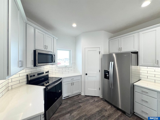 kitchen featuring backsplash, white cabinetry, dark wood-type flooring, and appliances with stainless steel finishes