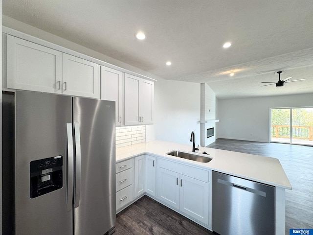 kitchen featuring sink, kitchen peninsula, decorative backsplash, white cabinetry, and stainless steel appliances