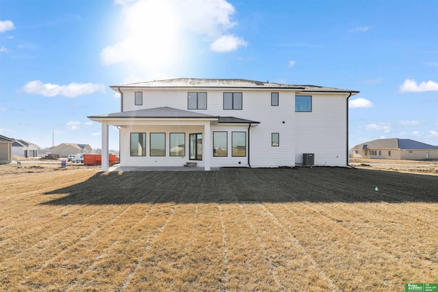 back of property with central AC unit, a yard, and a patio