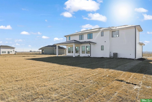 back of property featuring a lawn, cooling unit, and a patio