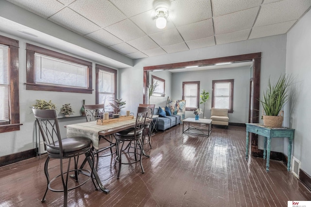 dining space featuring dark hardwood / wood-style flooring, plenty of natural light, and a paneled ceiling