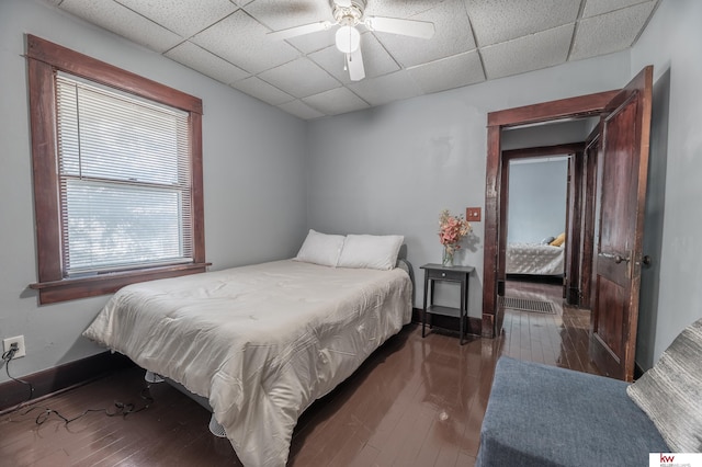 bedroom with a paneled ceiling, dark hardwood / wood-style floors, and ceiling fan