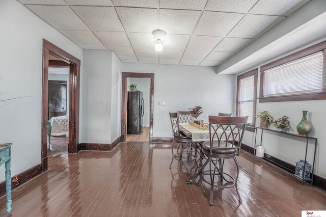 dining area featuring a drop ceiling and dark hardwood / wood-style flooring